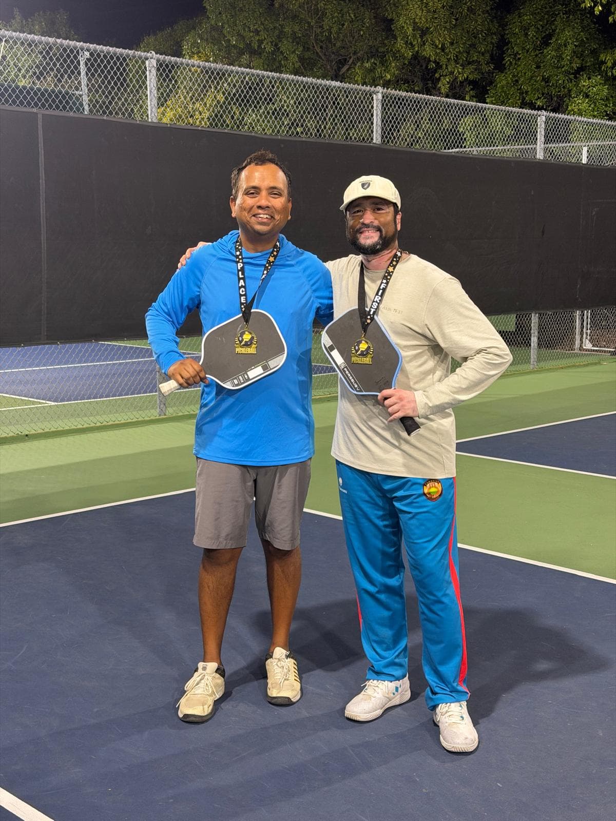 Abhinay and Nirav, Advanced champions, wearing their first-place medals on court.
